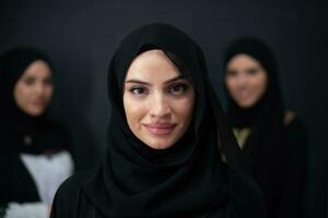 Group portrait of beautiful Muslim women in a fashionable dress with hijab isolated on black background photo