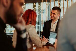 Group of business people hanging out in a coffee shop with a laptop amongst them. photo