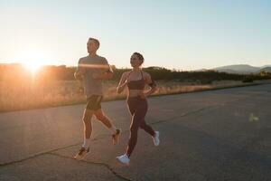 healthy young couple jogging in the city streets in the early morning with a beautiful sunrise in the background. photo