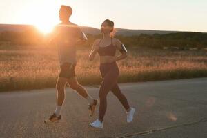 healthy young couple jogging in the city streets in the early morning with a beautiful sunrise in the background. photo