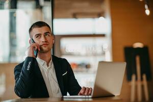 Happy business man sitting at cafeteria with laptop and smartphone photo