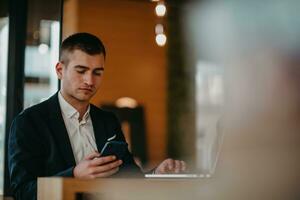 Happy business man sitting at cafeteria with laptop and smartphone photo