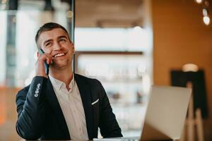 Happy business man sitting at cafeteria with laptop and smartphone photo
