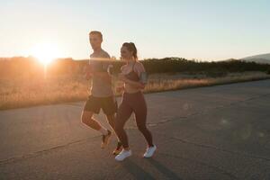 sano joven Pareja trotar en el ciudad calles en el temprano Mañana con un hermosa amanecer en el antecedentes. foto