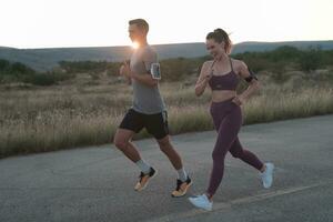 healthy young couple jogging in the city streets in the early morning with a beautiful sunrise in the background. photo