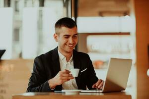 Happy business man sitting at cafeteria with laptop and smartphone. photo