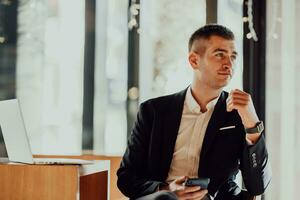 Happy business man sitting at cafeteria with laptop and smartphone photo