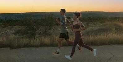 healthy young couple jogging in the city streets in the early morning with a beautiful sunrise in the background. photo