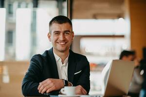 Happy business man sitting at cafeteria with laptop and smartphone photo