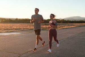 healthy young couple jogging in the city streets in the early morning with a beautiful sunrise in the background. photo