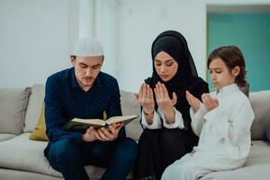 contento musulmán familia disfrutando el santo mes de Ramadán mientras Orando y leyendo el Corán juntos en un moderno hogar foto