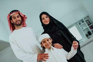 retrato de joven contento árabe musulmán familia Pareja con hijo en tradicional ropa gasto hora juntos durante el mes de Ramadán a hogar foto