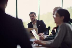 A diverse group of business professionals, including an person with a disability, gathered at a modern office for a productive and inclusive meeting. photo