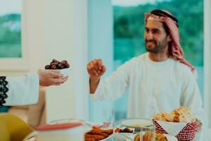 moderno multiétnico musulmán familia compartiendo un cuenco de fechas mientras disfrutando iftar cena juntos durante un Ramadán banquete a hogar foto