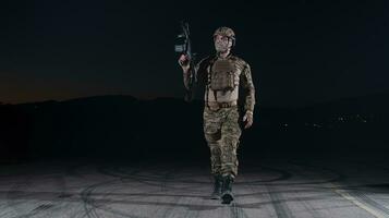 Ejército soldado en combate uniformes con un asalto rifle, plato portador y combate casco yendo en un peligroso misión en un lluvioso noche. foto