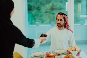 moderno multiétnico musulmán familia compartiendo un cuenco de fechas mientras disfrutando iftar cena juntos durante un Ramadán banquete a hogar foto