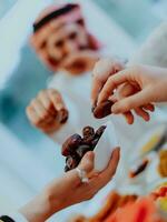 moderno multiétnico musulmán familia compartiendo un cuenco de fechas mientras disfrutando iftar cena juntos durante un Ramadán banquete a hogar foto