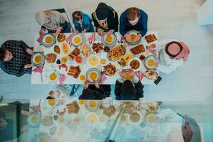 parte superior ver de musulmán familia teniendo iftar cena Bebiendo agua a descanso banquete. comiendo tradicional comida durante Ramadán banquete mes a hogar. el islámico halal comiendo y Bebiendo en moderno hogar foto