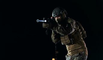 Army soldier in Combat Uniforms with an assault rifle, plate carrier and combat helmet going on a dangerous mission on a rainy night. photo