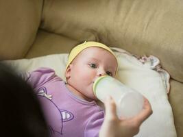 baby  eating milk from bottle photo