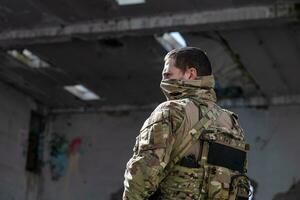 Army soldier in Combat Uniforms with an assault rifle and face protection mask. photo