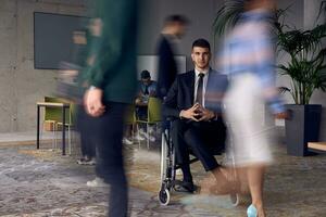 A businessman in a wheelchair in a modern office, surrounded by his colleagues who are portrayed with blurred movements, symbolizing their support and solidarity as they navigate the workspace together. photo