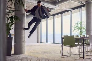 In the modern office, a businessman with a briefcase captivates everyone as he performs thrilling aerial acrobatics, defying gravity with his daring leaps and showcasing his agility with breathtaking showmanship. photo