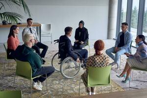 A businessman in a wheelchair in the center of the circle, passionately sharing his business ideas with his colleagues, fostering an atmosphere of collaboration and innovation in a dynamic and engaging workplace. photo