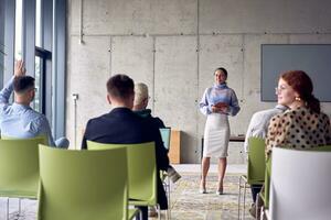 A group of young business professionals in a modern office attentively listens to colleague presentation, showcasing a dynamic and collaborative atmosphere as they exchange ideas and strive for success. photo