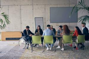 A diverse group of business professionals, including an person with a disability, gathered at a modern office for a productive and inclusive meeting. photo