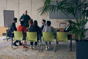 In a modern office setting, a group of business professionals attentively listens to a captivating presentation delivered by their young colleagues, showcasing their teamwork, engagement, and eagerness to learn and grow in a collaborative environment. photo