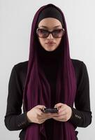 mujer en negro elegante de moda ropa musulmán Pañuelo. dama utilizando inteligente teléfono, cerca arriba retrato de sonriente medio oriental muchacha. foto