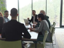 A diverse group of business professionals, including an person with a disability, gathered at a modern office for a productive and inclusive meeting. photo