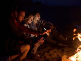 Couple enjoying with friends at night on the beach photo