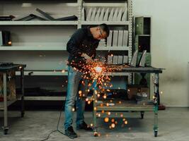 Heavy Industry Engineering Factory Interior with Industrial Worker Using Angle Grinder and Cutting a Metal Tube. Contractor in Safety Uniform and Hard Hat Manufacturing Metal Structures. photo