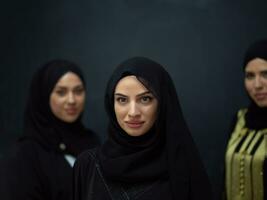 Group portrait of beautiful Muslim women in a fashionable dress with hijab isolated on black background photo