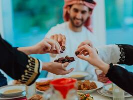 moderno multiétnico musulmán familia compartiendo un cuenco de fechas mientras disfrutando iftar cena juntos durante un Ramadán banquete a hogar foto