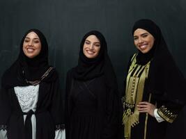 grupo retrato de hermosa musulmán mujer en un de moda vestir con hijab aislado en negro antecedentes foto