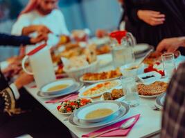 eid Mubarak musulmán familia teniendo iftar cena Bebiendo agua a descanso banquete. comiendo tradicional comida durante Ramadán banquete mes a hogar. el islámico halal comiendo y Bebiendo foto