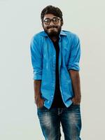 Indian smiling young man with blue shirt and glasses posing on gray background photo