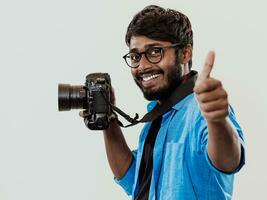 Professional photographer having DSLR camera taking picture.Indian man photography enthusiast taking photo while standing on blue background. Studio shot