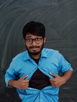 A symbolic photo of an Indian boy showing the superman sign in front of the school blackboard