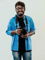 Professional photographer having DSLR camera taking picture.Indian man photography enthusiast taking photo while standing on blue background. Studio shot