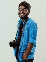 Professional photographer having DSLR camera taking picture.Indian man photography enthusiast taking photo while standing on blue background. Studio shot