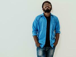 Indian smiling young man with blue shirt and glasses posing on gray background photo