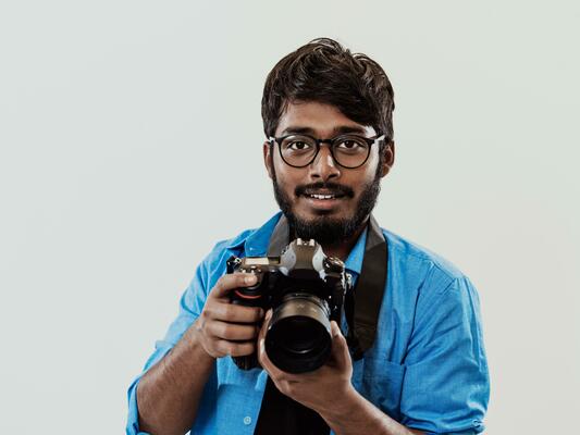 Professional photographer having DSLR camera taking picture.Indian