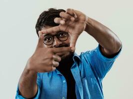 Young handsome man focusing with fingers, framing with hands isolated on grey background. Close up portrait photo