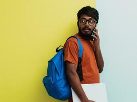 Indian student with blue backpack, glasses and notebook posing on gray and green background. The concept of education and schooling. Time to go back to school photo