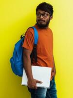 indio estudiante con azul mochila, lentes y cuaderno posando en verde antecedentes. el concepto de educación y enseñanza. hora a Vamos espalda a colegio foto