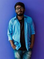 indio estudiante con azul mochila, lentes y cuaderno posando en verde antecedentes. el concepto de educación y enseñanza. hora a Vamos espalda a colegio foto